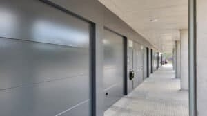 Façana de la filera de cases Palau-Solità. Portes de garatge grises, porxo de formigó.