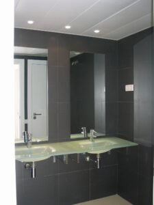 Interior bany modern amb doble lavabo de vidre i rajoles fosques. Projecte 2008 Ctra Barcelona.