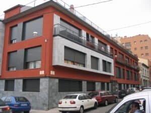 Vista en cantonada d’un edifici residencial a Sabadell amb balcons, façana ceràmica i sòcol de pedra