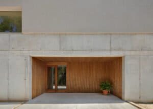 Façana de formigó vist i fusta amb entrada minimalista. Projecte Enrique Lanfranco 2023.