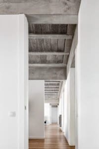 Passadís interior Casa Ullastrell amb sostre de formigó vist i parquet de fusta.