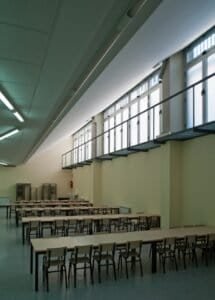 Refectori modern de Carmelites amb grans finestrals, llum natural, taules i cadires.