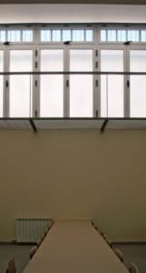 Carmelites: Interior de sala amb grans finestrals superiors i taula llarga.