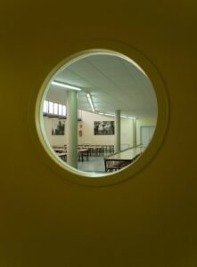 Interior menjador modern de Carmelites, vist per finestreta circular.