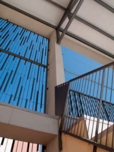 Detall constructiu d'arquitectura moderna amb brisesol, escala i barana metàl·lica.