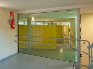 Interior modern Carmelites: passadís amb gran envà de vidre i parets grogues.