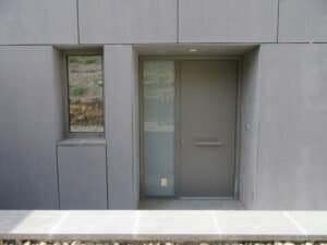 Entrada minimalista Casa Ullastrell: porta grisa