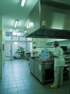 Interior de cuina professional moderna per a les Carmelites, amb cuiners treballant.