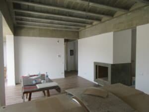 Sala d'estar Casa Ullastrell amb sostre de formigó vist i llar de foc integrada.