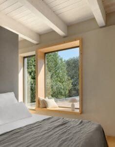 Dormitori amb sostre de bigues de fusta en una casa unifamiliar d’obra nova