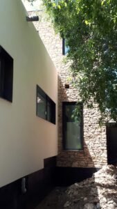 Porxo exterior amb estructura lleugera i ombres en habitatge unifamiliar