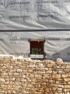 Detall de finestra i mur de pedra en façana d’habitatge unifamiliar