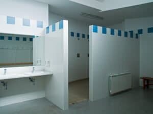 Interior funcional amb lavabos, dutxes i revestiments blaus i blancs, Carmelites escollides.