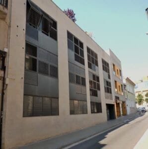 Edifici plurifamiliar a Sabadell amb façana de pedra natural i gelosies metàl·liques a les finestres