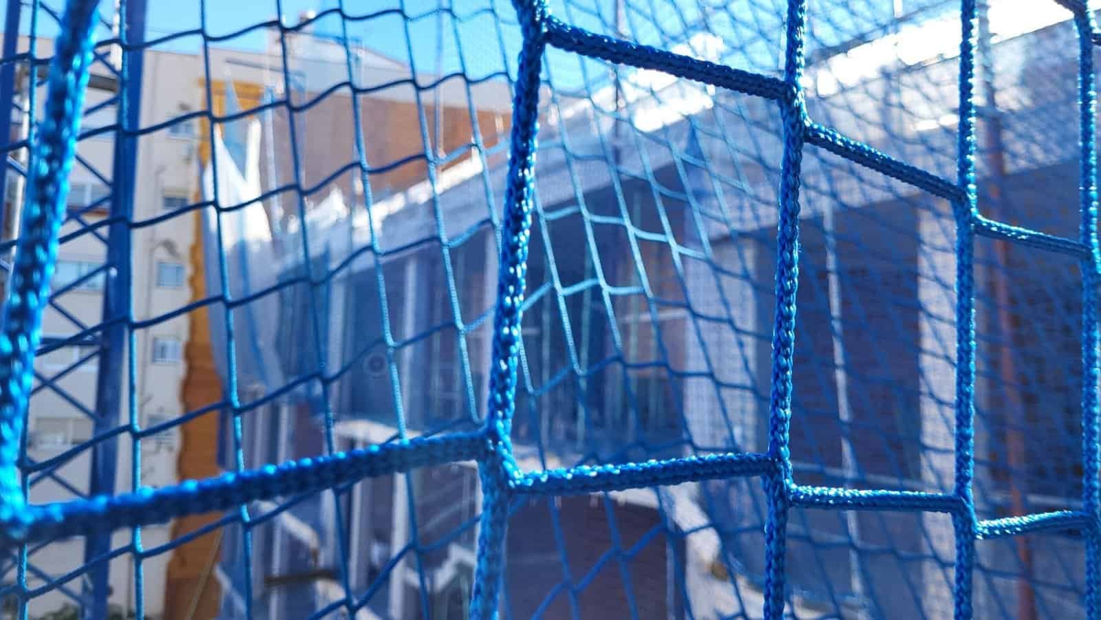 Xarxa de seguretat en obra de construcció amb edifici en segon pla